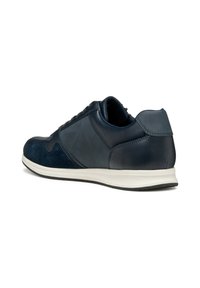 Sneaker bassa blu navy con pannelli in pelle e suede misti, suola bianca e colletto imbottito, vista da un angolo laterale posteriore.