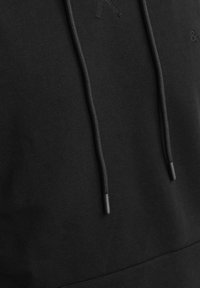 Black hoodie with textured fabric, featuring a kangaroo pocket, adjustable drawstrings, and subtle logo detail. Soft and comfortable design.