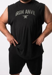 Černé svalové tílko s potiskem "IRON ANVIL" v šedé barvě, spárované s černými šortkami. Tkanina vypadá lehce a prodyšně.