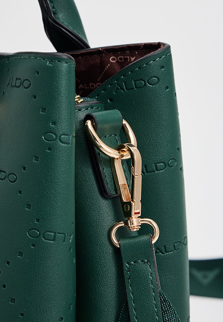 Sac à main en simili cuir vert avec logo en relief, quincaillerie dorée, fermeture zippée et bandoulière amovible. Texture lisse et design structuré.