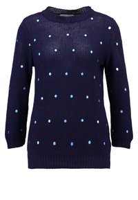 Marinblå stickad tröja med rund halsringning och långa ärmar, dekorerad med ljusblå och vita prickar som är jämnt fördelade över hela plagget.