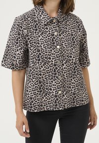 Camicia a maniche corte con stampa leopardata in beige e nero, dotata di chiusura con bottoni e colletto classico. Tessuto morbido con una superficie liscia.