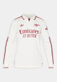 Langærmet hvid fodboldtrøje med et struktureret mønster, maroon detaljer og krave. Har "Emirates Fly Better" logoet fremtrædende.