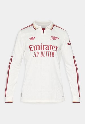 Långärmad, vit fotbollsjacka med strukturerat mönster, vinröda accenter och krage. Har "Emirates Fly Better"-logotypen i framträdande ställning.