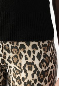 Melnas ribu adījuma krekls savienots ar legingiem, kas izceļas ar brūnu un melnu leoparda rakstu. Legingi ir ar mīkstu auduma tekstūru.