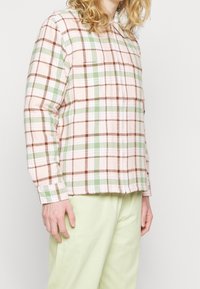Checkered shirt in soft fabric, featuring pink, green, and brown hues. Straight-cut design with button closure and long sleeves.