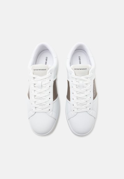 Paire de baskets basses blanches avec des bandes taupe sur les côtés, des lacets blancs et le logo Emporio Armani sur les languettes et les semelles intérieures.