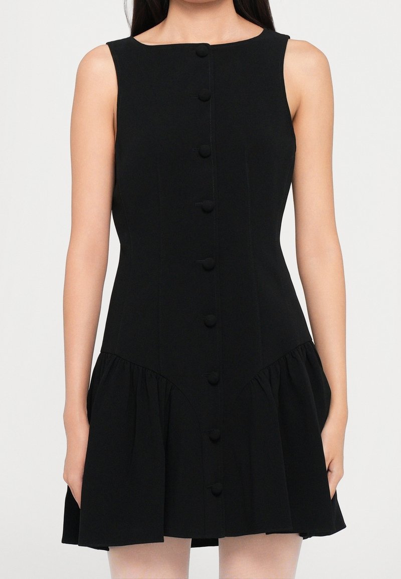 Robe noire sans manches avec un corsage ajusté, une patte de boutonnage devant et une jupe froncée évasée se terminant au-dessus des genoux.