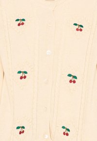 Roomkleurig gebreid vest met verticale kabelpatronen en geborduurde rode kersen met groene bladeren, dichtgeknoopt met witte knopen in het midden.