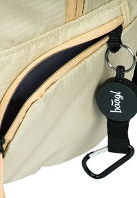 Borsa in tessuto beige con superficie testurizzata, tasca con zip di colore marrone chiaro e un portachiavi in metallo nero staccabile.