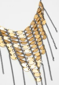 Goudkleurige metalen ketting met gelaagde, halve cirkels bevestigd door een zwarte ketting, met een watervalontwerp en fijne details.