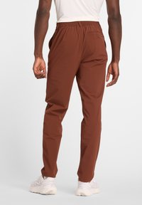 Pantaloni marroni leggeri con vita elastica, taglio a gamba dritta, tasche laterali e una tasca posteriore singola con dettaglio a bottone.