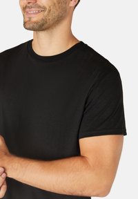 Black cotton t-shirt with short sleeves and a crew neckline, featuring a smooth texture and a fitted design.