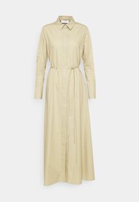 Longue robe chemise beige avec col pointu, manches longues, devant à boutons cachés et ceinture fine nouée à la taille.