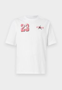 Λευκό κοντομάνικο μπλουζάκι με κόκκινο αριθμό 23 στο αριστερό στήθος και μαύρο λογότυπο Jumpman με κόκκινο κείμενο "Jordan" στο δεξί στήθος.