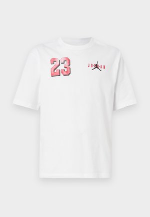 Λευκό κοντομάνικο μπλουζάκι με κόκκινο αριθμό 23 στο αριστερό στήθος και μαύρο λογότυπο Jumpman με κόκκινο κείμενο "Jordan" στο δεξί στήθος.