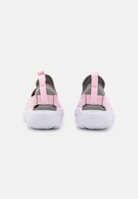 Des chaussures slip-on roses et grises avec une tige en tissu doux, des boucles au talon pour un enfilage facile, et une semelle extérieure en caoutchouc blanc avec des motifs de traction.