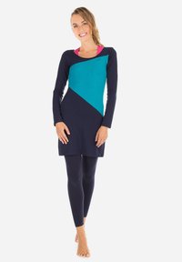 Marinblå långärmad tunika med turkos geometrisk design, matchad med marinblå leggings. Mjuk, elastisk tyg som har en rund halsringning och lagerlook.