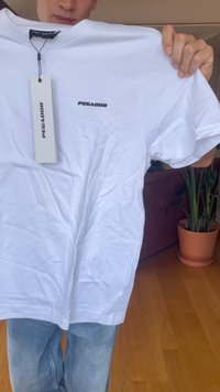 Balta medvilnės marškinėliai su apvaliu iškirpimu, trumpomis rankovėmis ir juodu "PEGADOR" logotipu ant krūtinės. Prikabintas pardavimo etiketė.