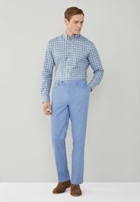 Camicia a quadri blu chiaro, con bottoni, slim-fit. Abbinata a pantaloni blu pallido e scarpe in camoscio marroni. Tessuto liscio, design classico.