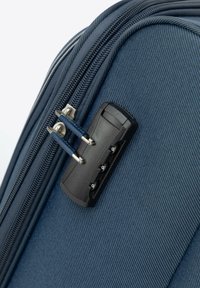 Roh klasické tašky na textil v námořnické modři má dvojitý zip s černým kombinovaným zámkem a modrými kovovými táhly, což vše podtrhuje texturovaný povrch.