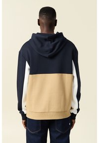 Felpa con cappuccio caratterizzata da blocchi di colore blu navy, beige e bianco; texture liscia, orlo e polsini a costine; vista posteriore che mette in evidenza il design.