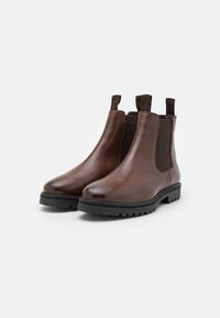 Botas Chelsea de cuero marrón con paneles laterales elásticos y lengüetas de tira. Punta redonda y suela de goma con textura para un mejor agarre.