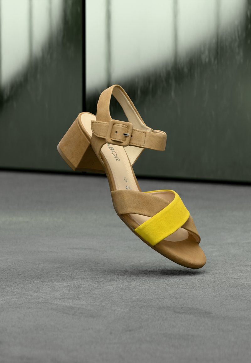 Sandales à talons en daim beige avec une bride accent jaune, un design incurvé, une boucle réglable et un talon épais effilé.