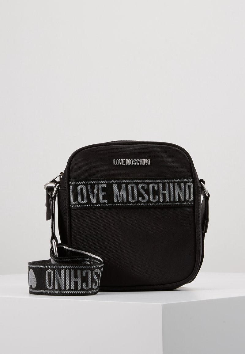Černá nylonová crossbody taška ve tvaru obdélníku, s prostornými přihrádkami a popruhem s textem "LOVE MOSCHINO" tkaným šedou barvou.