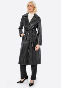 Černý kožený trenčkot s páskem v pase, velkým límcem a dlouhými rukávy. Obsahuje dvě boční kapsy a zapínání na knoflíky. Hladká textura.