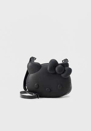 Schwarze Umhängetasche in Form eines Cartoon-Katzenkopfes mit einer Schleife am Ohr und verstellbarem Riemen vor weißem Hintergrund.