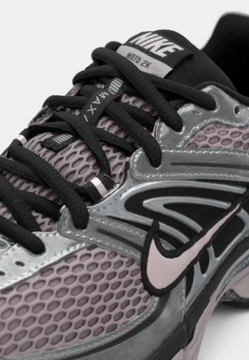 Zapatillas Nike Air Max 2K en gris con acentos negros. Presentan parte superior de malla, suela de goma, collar acolchado y logotipo en contraste.