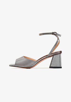 Stříbrné sandály na blokovém podpatku s otevřenou špičkou, s texturovaným metalickým svrškem a tenkým páskem okolo kotníku, který je zajištěn přezkou.