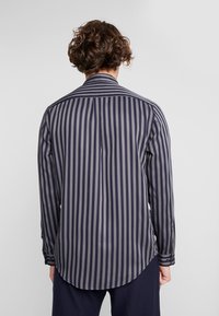 Camicia a maniche lunghe a righe blu navy e grigie, realizzata in tessuto morbido, con orlo curvo e polsini con bottone.