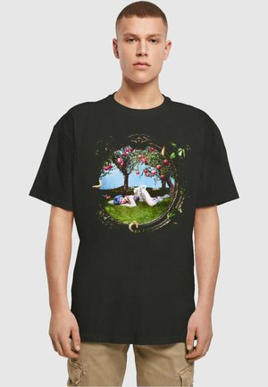 Schwarzes T-Shirt mit einem kreisförmigen Grafikdesign, das grüne Bäume, rote Äpfel und eine liegende Figur in einer verspielten Landschaft zeigt, alles kunstvoll umrandet.