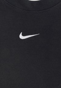 Svart bomull t-shirt med rund hals och korta ärmar, med en vit broderad Nike swoosh-logotyp på bröstet. Slät textur.