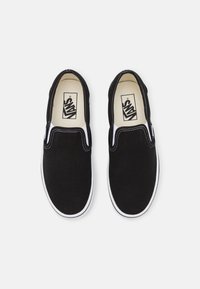 Black canvas slip-on shoes with white accents. Rounded toe, double elastic side panels, and a white rubber sole. Logo on insole.