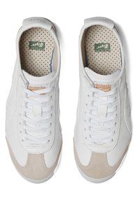 Et par hvide Onitsuka Tiger sneakers med beige ruskind toe caps og hvide snørebånd, set ovenfra på en hvid baggrund.