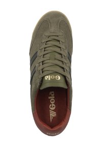 Vihreät mikrokuosisneakerit mustilla raidoilla, pyöröitä kärjellään, kultaisella brändäyksellä ja punaisella sisäosalla. Varusteena tasaiset nauhat ja kumipohja.