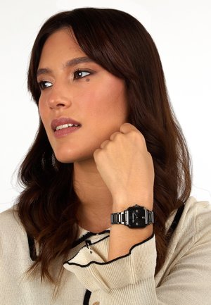 Orologio digitale nero con dettagli argento su un bracciale in metallo a motivo. L'orologio presenta un quadrante ottagonale e un display ben leggibile.