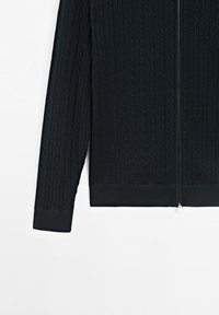 Maglione nero a maniche lunghe in maglia con motivo a treccia e cerniera frontale argentata, polsini e orlo a coste, esposto su sfondo bianco.