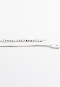 Zilveren ketting met twee secties: de ene is een gladde, platte schakelketting, de andere heeft ronde en met elkaar verbonden schakels; voorzien van een kreeftsluiting.