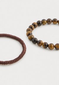 Barna fonott zsinórból készült karkötő és egy kerek gyöngyökkel készült karkötő, amely tigrisszem kövekből áll barna és arany árnyalatokban, sima felülettel.