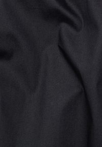 Tessuto nero con una texture liscia, che mostra sottili variazioni di ombreggiatura e pieghe leggere, indicative di un materiale flessibile.