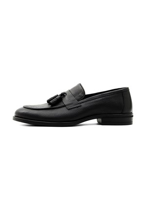Schwarzer Herrenschuh aus Leder mit Quasten, niedrigem Absatz und strukturierter Oberfläche, seitlich vor weißem Hintergrund dargestellt.