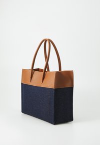 Brown leather top with two handles, paired with a dark blue denim body. Rectangular shape with a textured surface and contrast stitching.
