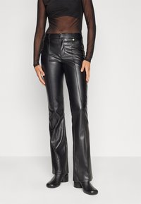 Pantalon évasé en cuir noir avec un détail de couture avant, taille haute, deux poches et des accents de boutons dorés. Texture lisse avec une finition élégante.
