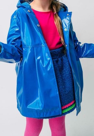 Blå, blank regnjakke med hætte, metaltrykknapper og to forlommer. Bæres over en lyserød top og en struktureret blå nederdel med farverige detaljer.