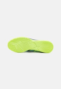 Suela de zapato en neumático verde neón brillante con un patrón texturizado para mayor agarre, con un borde azul de contraste.