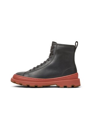Stivali alla caviglia in pelle nera con suola in gomma rossa, caratterizzati da punta tonda, design con lacci e linguetta posteriore per una facile calzata.